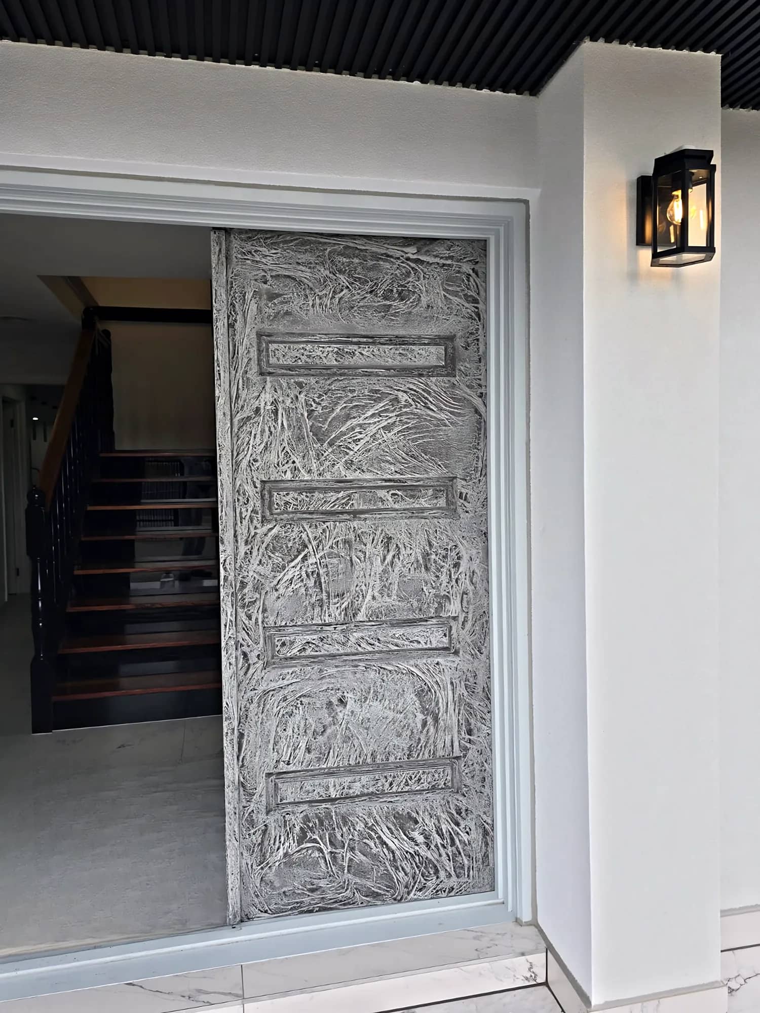 Tall pivot entry door with a hand-applied textured feature finish on a modern white facade