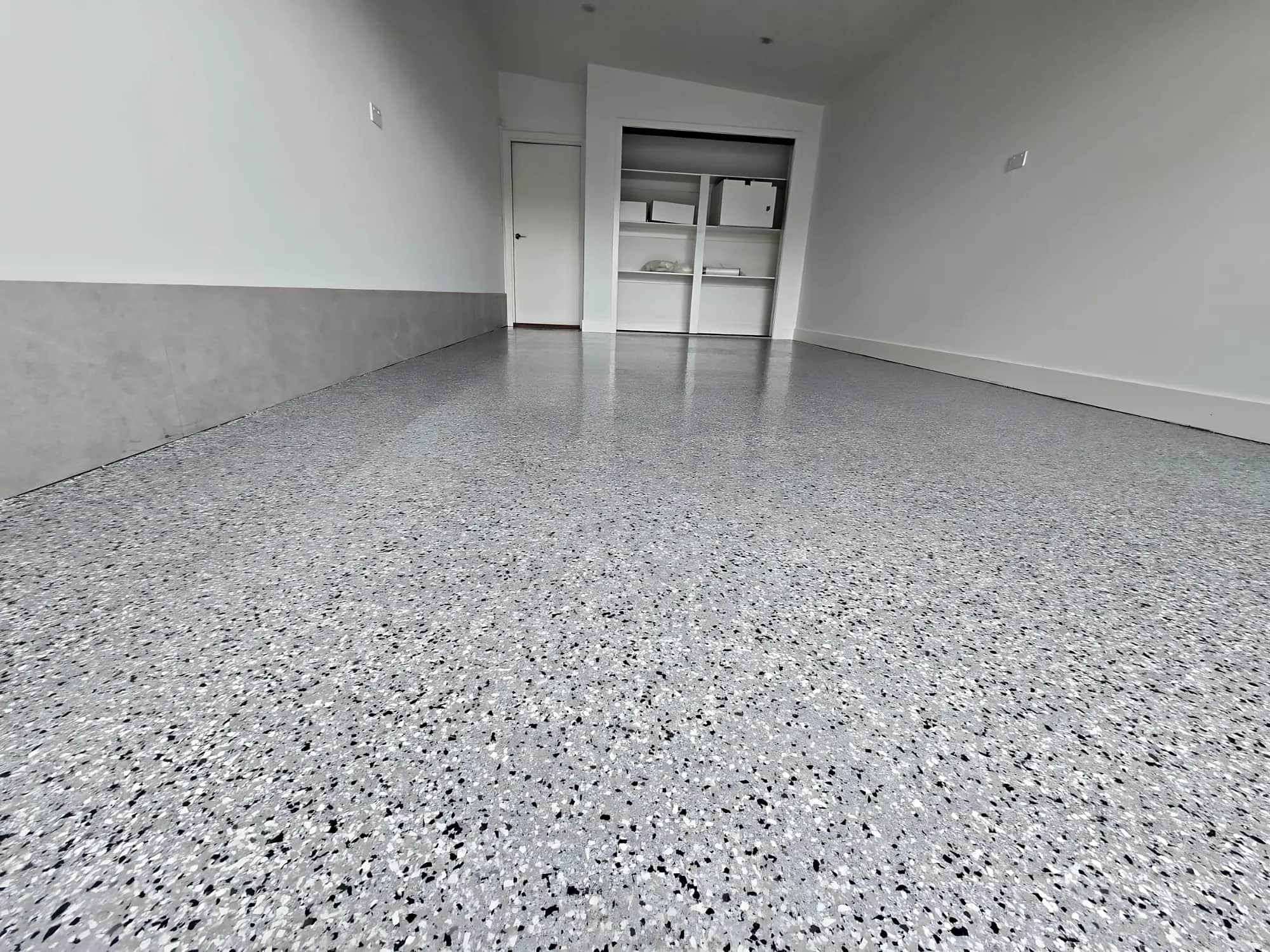High-gloss grey full-flake epoxy garage floor with white walls and an open roller door