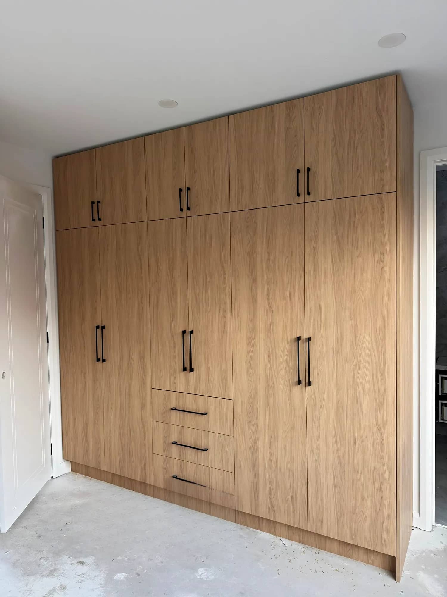 Full-height built-in wardrobe with oak-look doors and black handles