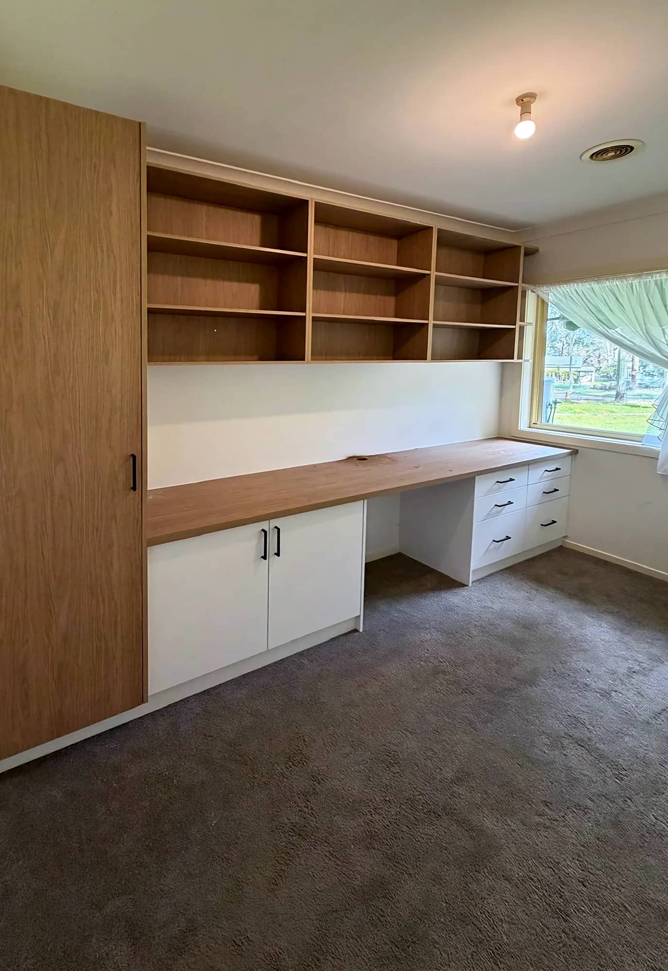 Built-in study nook with an oak-look desk, open shelving and white drawers
