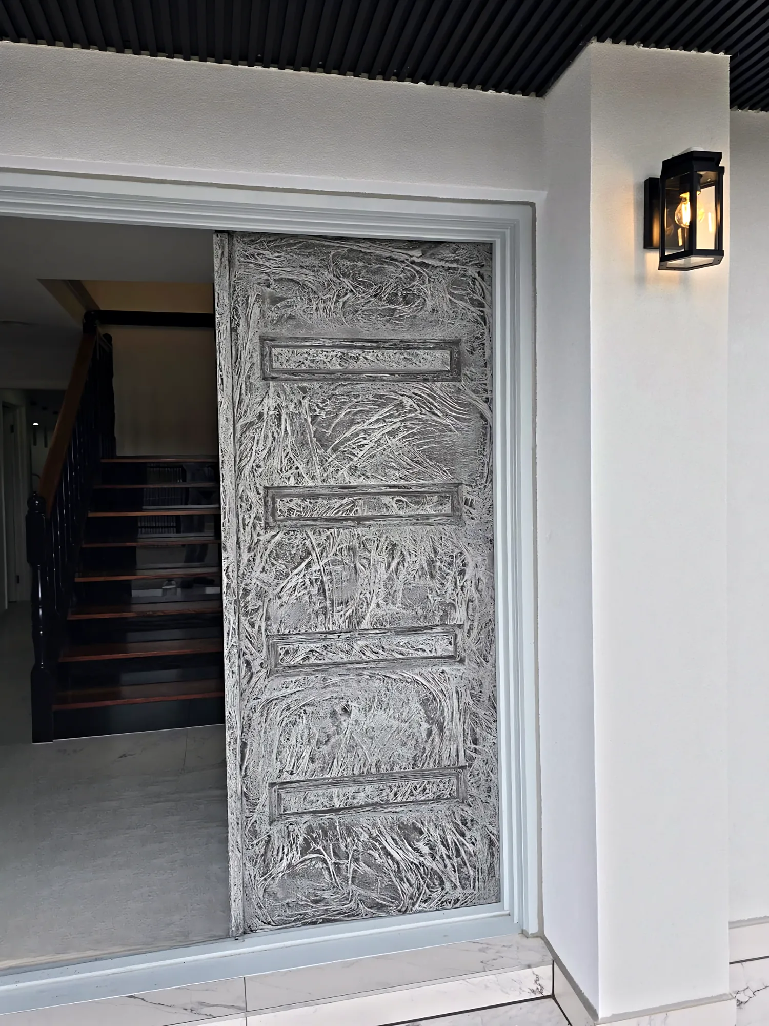 Tall pivot entry door with a hand-applied textured feature finish on a modern white facade