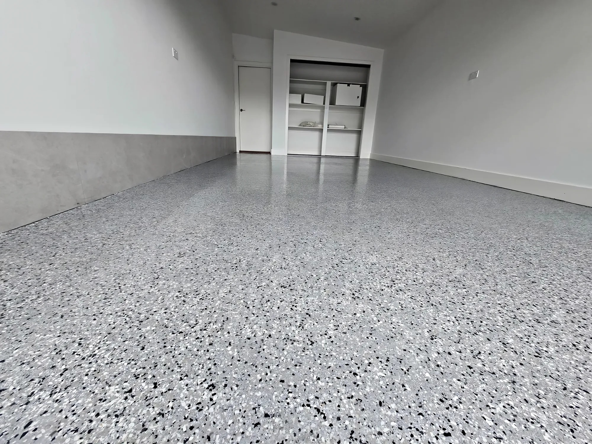 High-gloss grey full-flake epoxy garage floor with white walls and an open roller door