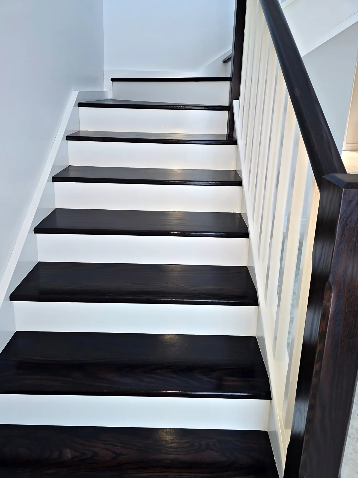 Staircase with dark-stained timber treads and handrail, white risers and white balusters